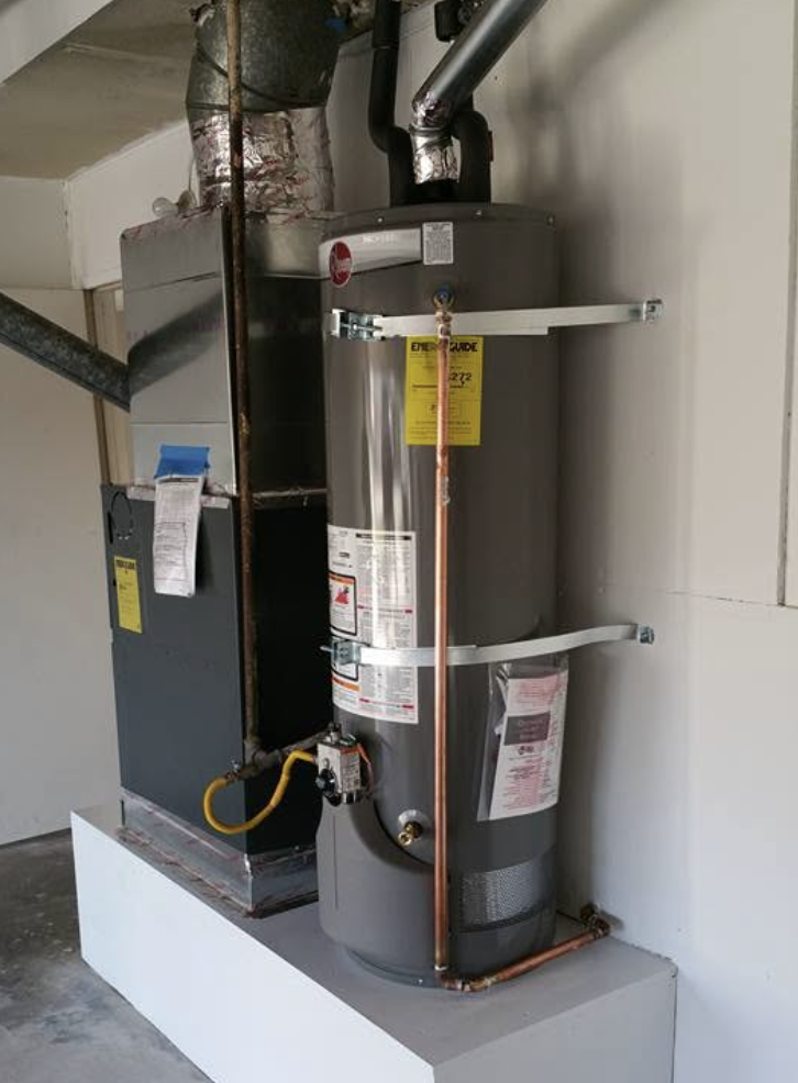 Furnace and Rheem water heater installed on a raised platform in a garage utility space